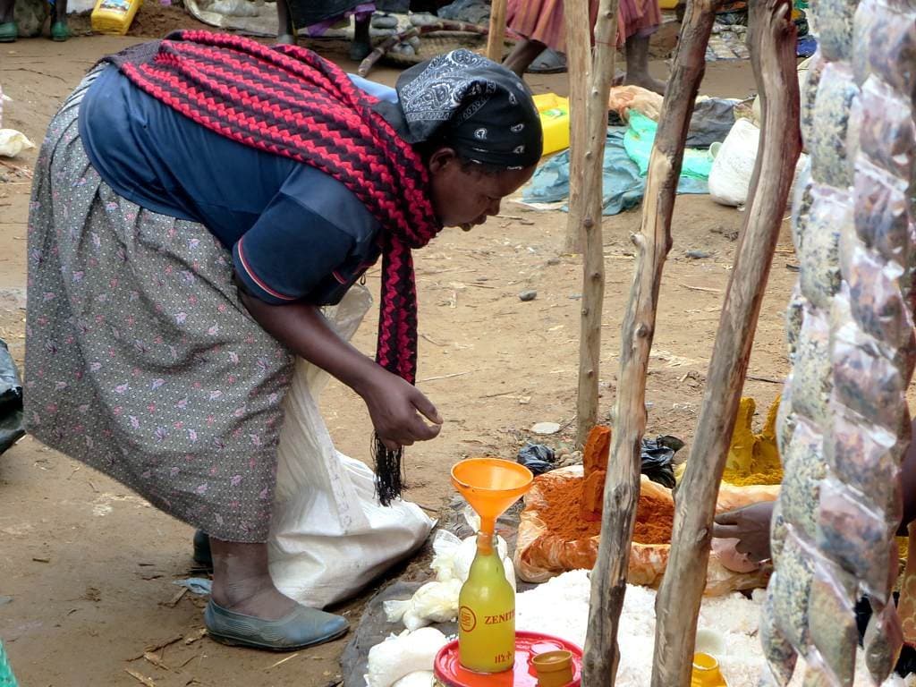 A woman bending over sacks of red berbere and other spices at an open-air market