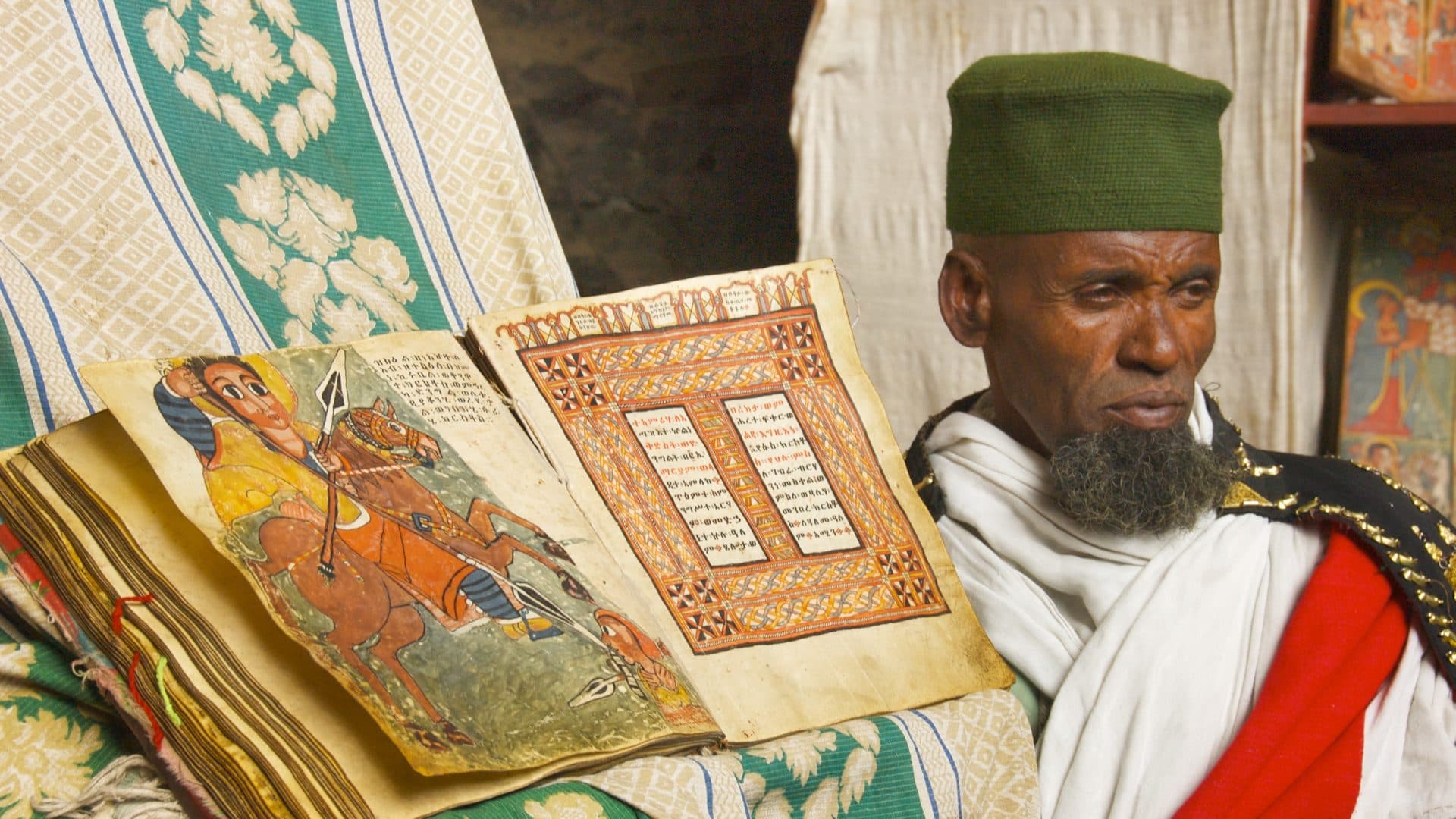 An Ethiopian Orthodox monk seated beside an open illuminated manuscript at the monastery of Na'akuto La'ab