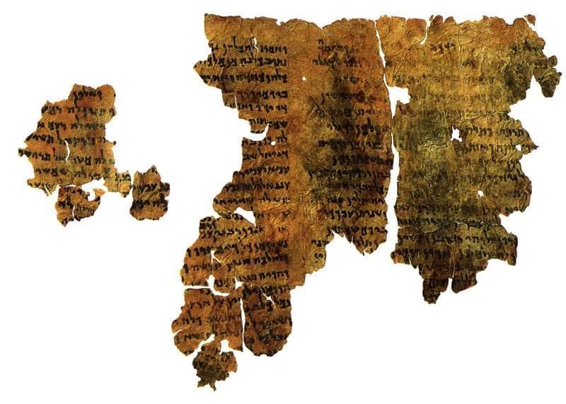 Dark, irregular fragments of an ancient scroll covered in small Aramaic letters