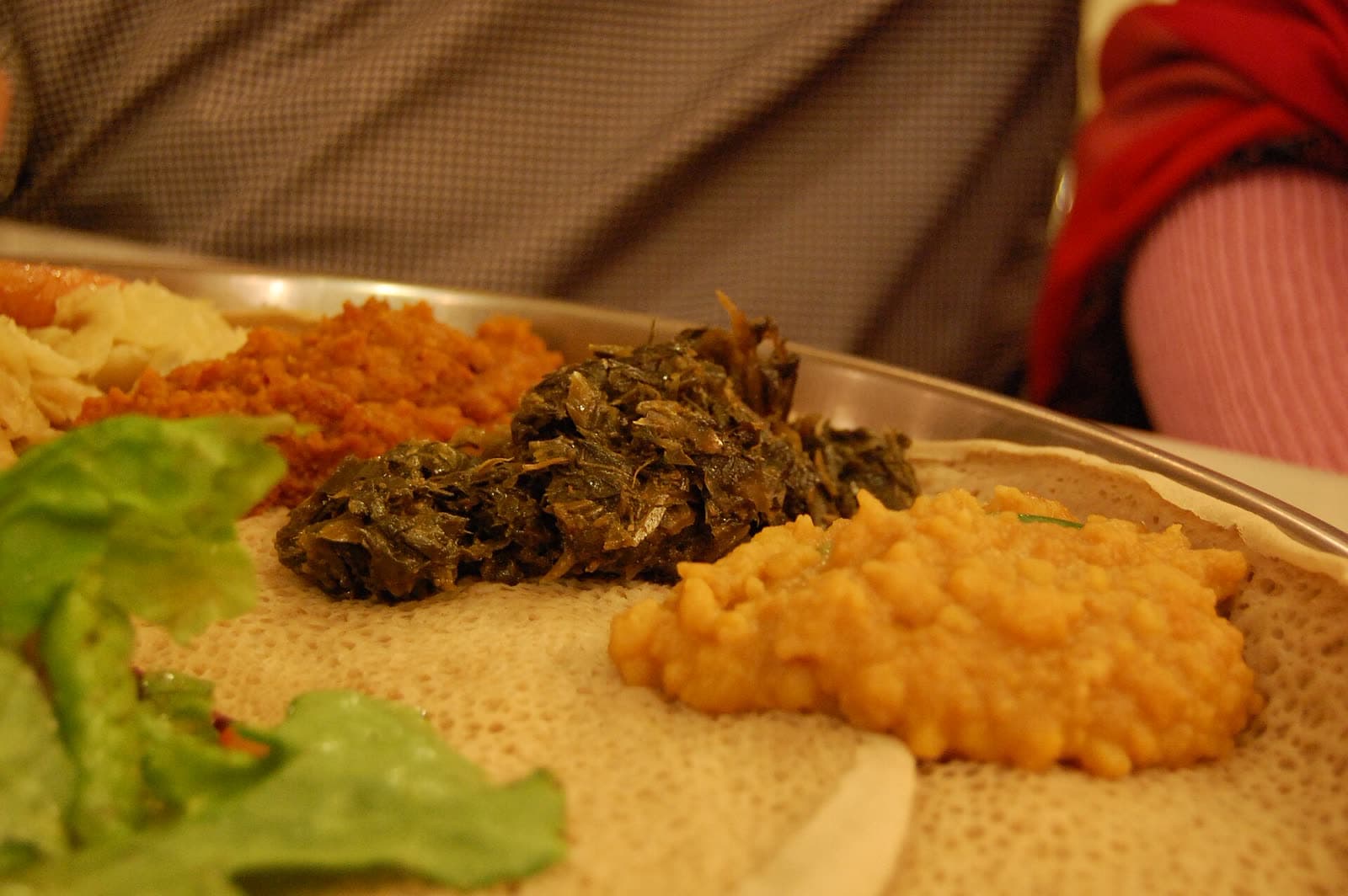 Yellow kik alicha, red misir wat and dark green gomen side by side on injera