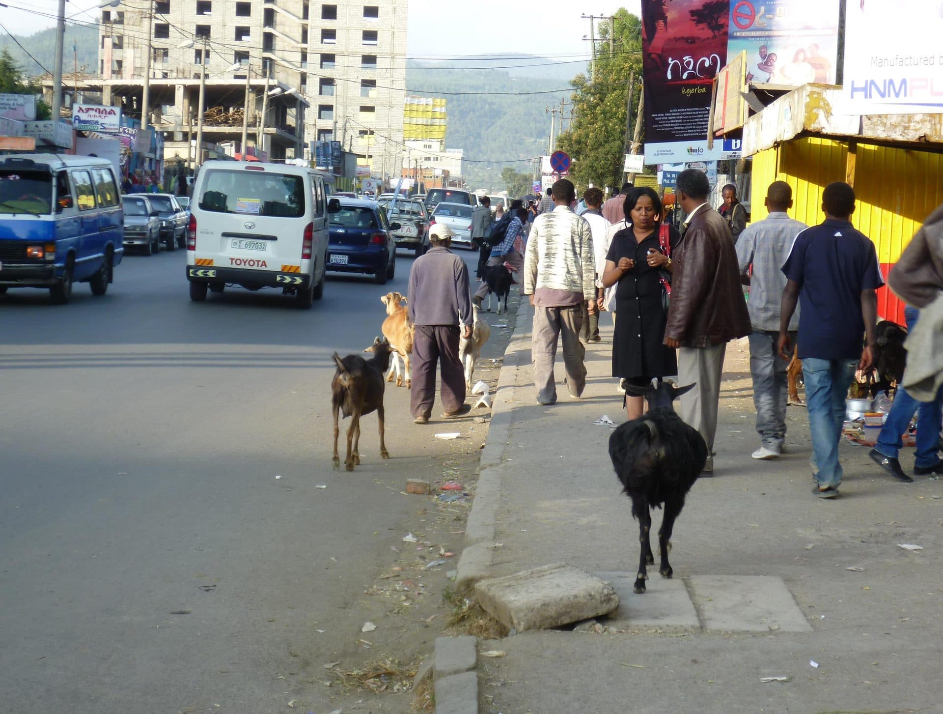 A busy street in Addis Ababa with minibuses, pedestrians and shops along the sidewalk
