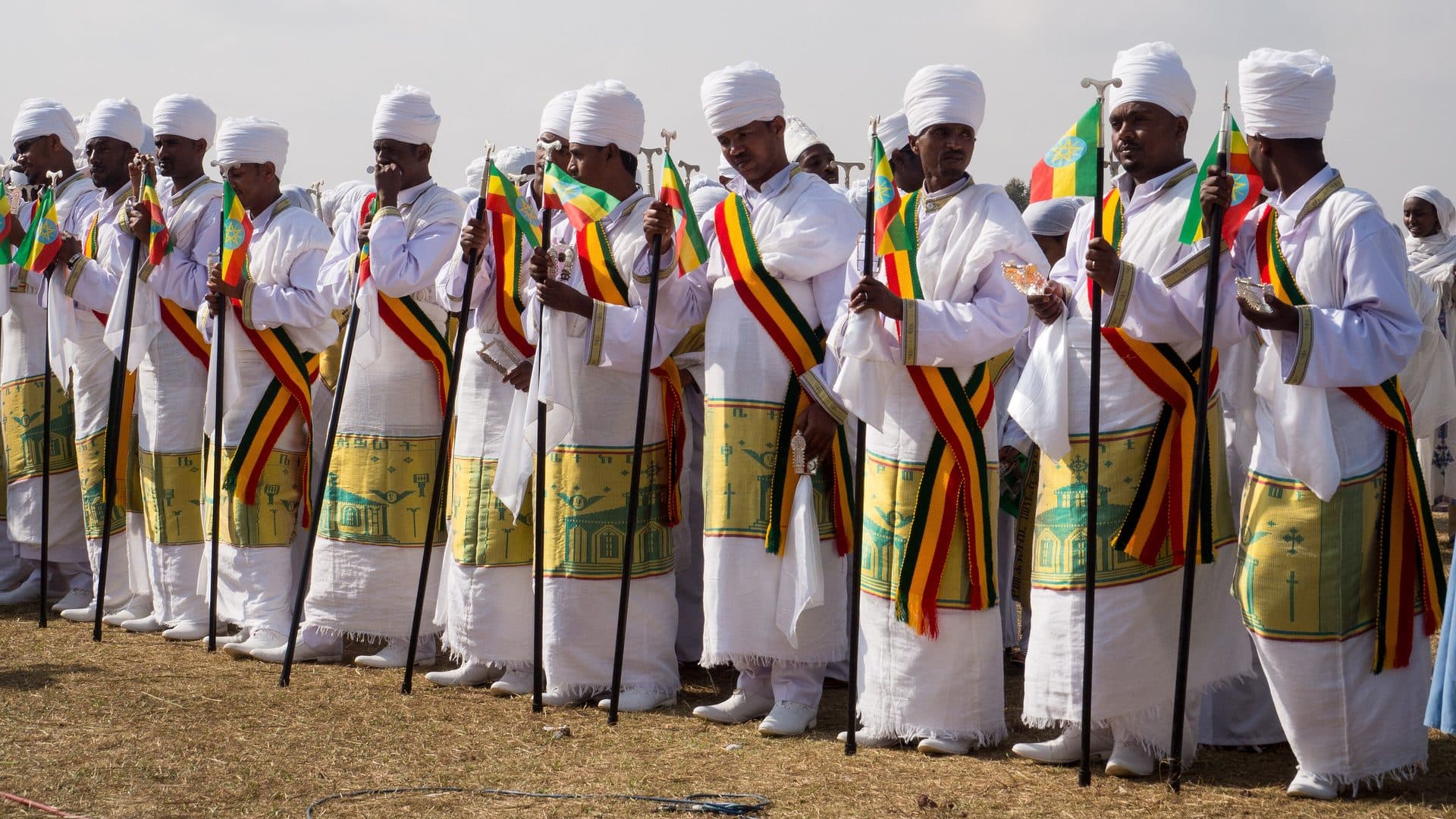 Ethiopian Orthodox priests in embroidered robes under ornate umbrellas at a Timket celebration