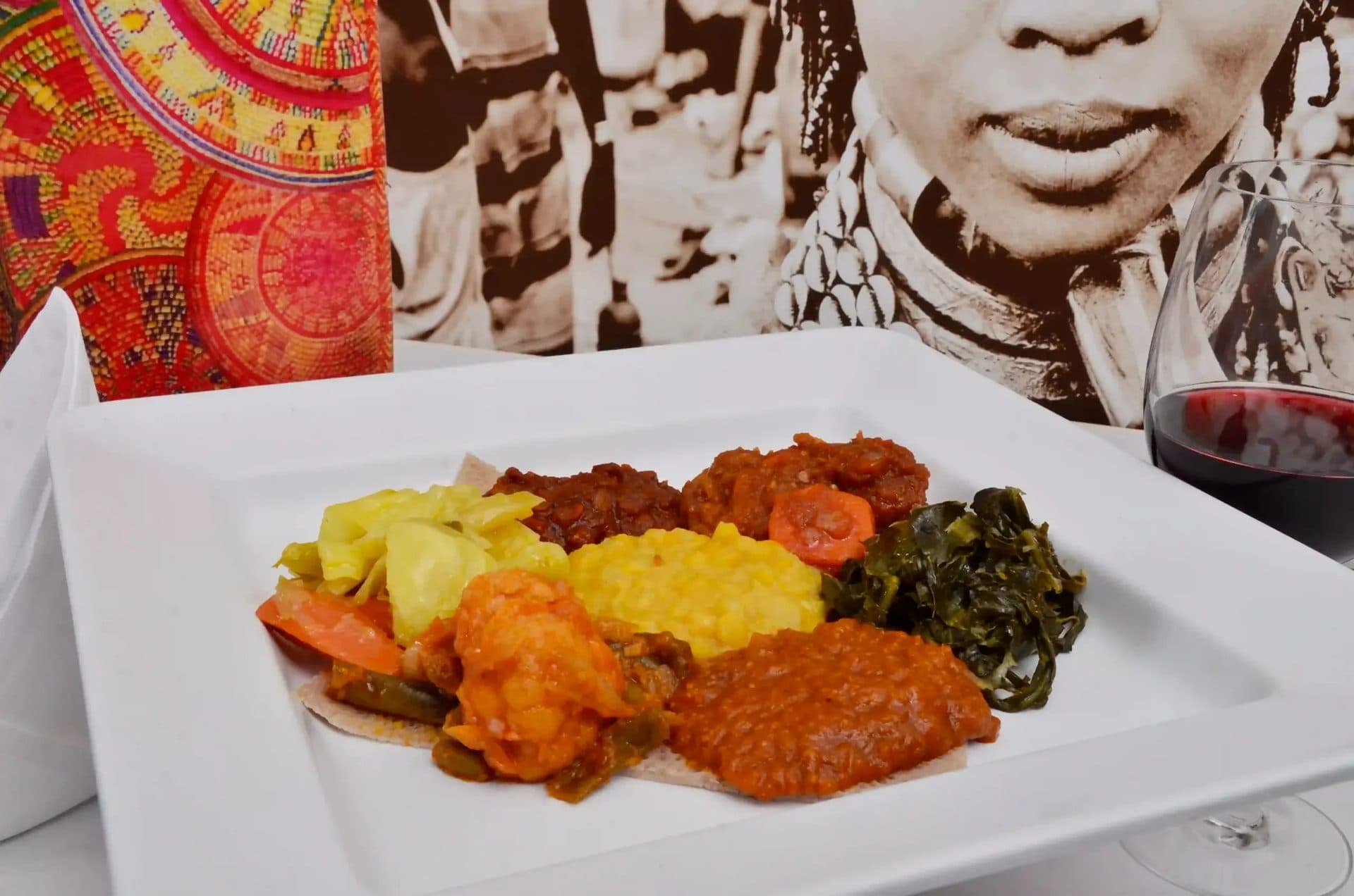 A plate of Ethiopian stews, greens and vegetables with a glass of red wine at Das Ethiopian in Georgetown